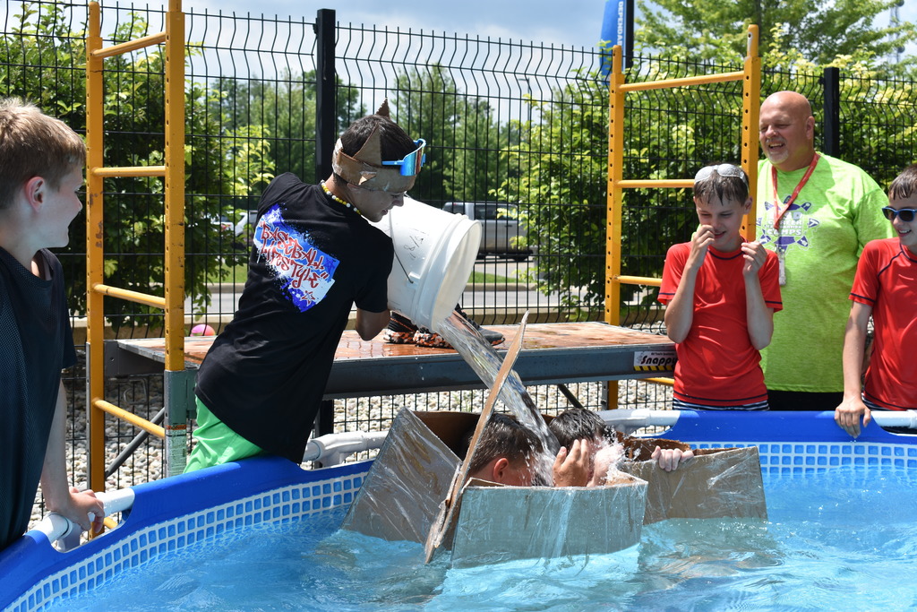 Two campers float in their boat while a camper fills it with water