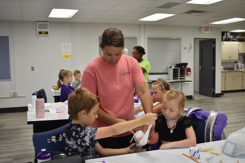 Teacher helping two students learn to wrap an injury