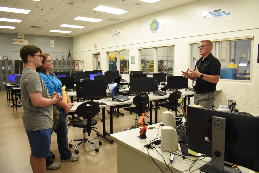 An instructor chatting with a family about Robotics