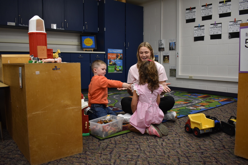 A student helping a fellow student who was having a hard time while the teacher looks on