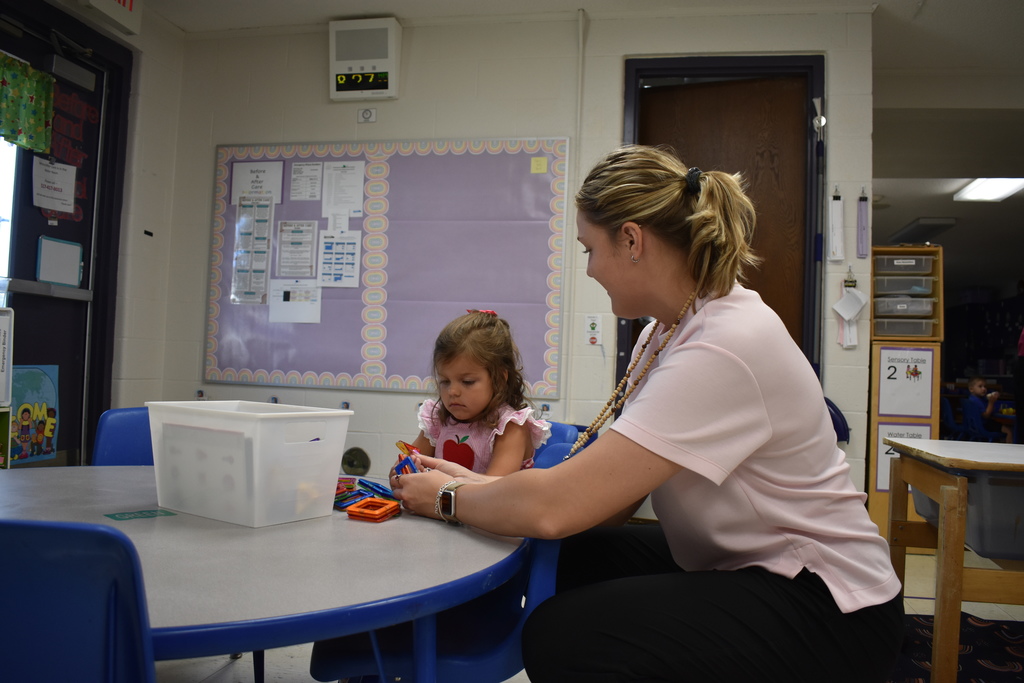 A student learning a new activity with a teacher assisting 