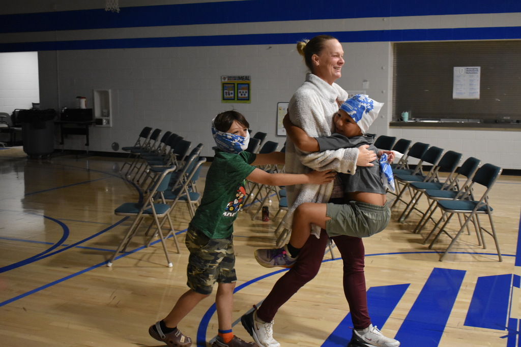 Two students welcoming an instructor by jumping on her as  she joins their team