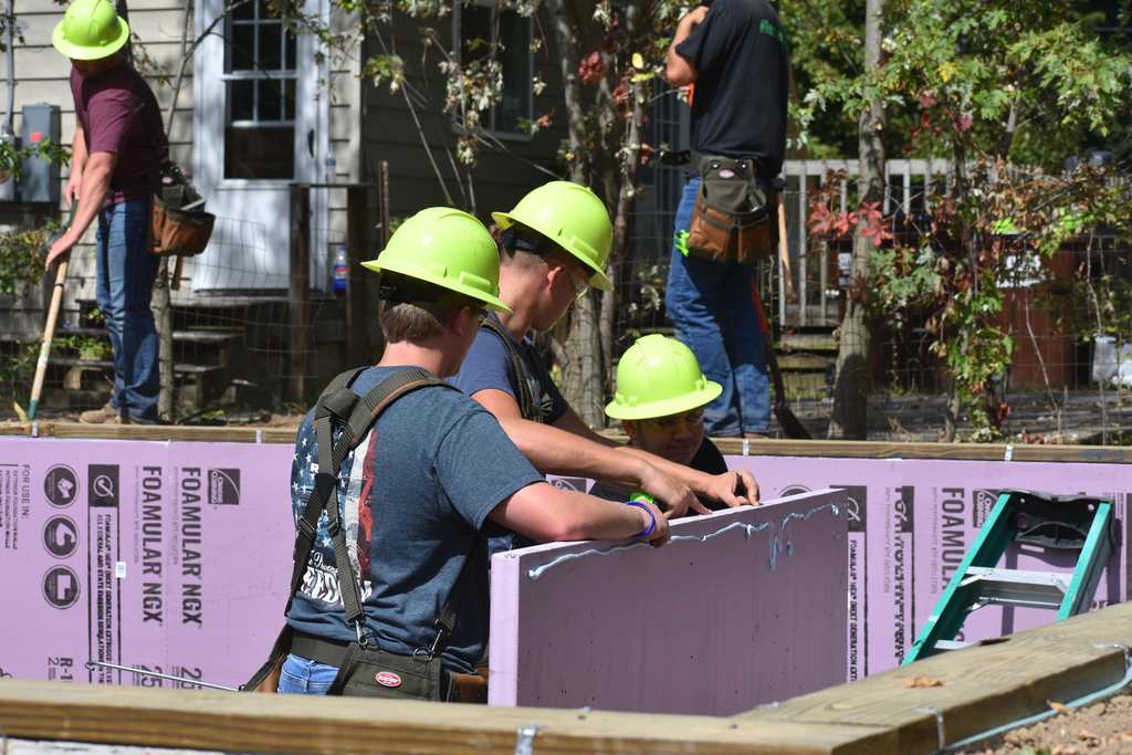 Three students putting up a foam wall