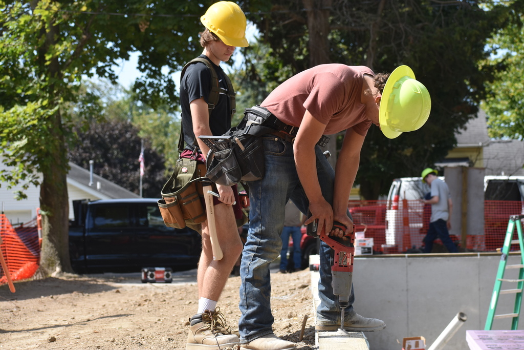 A student drilling holes while one looks on