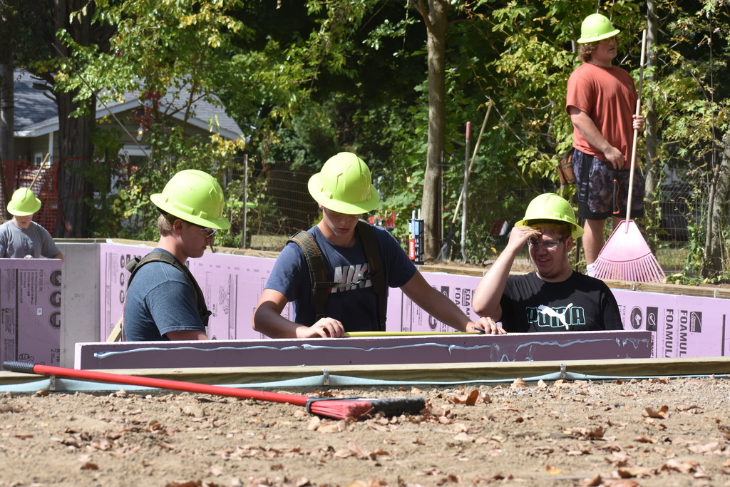 three students measuring a wall before placement
