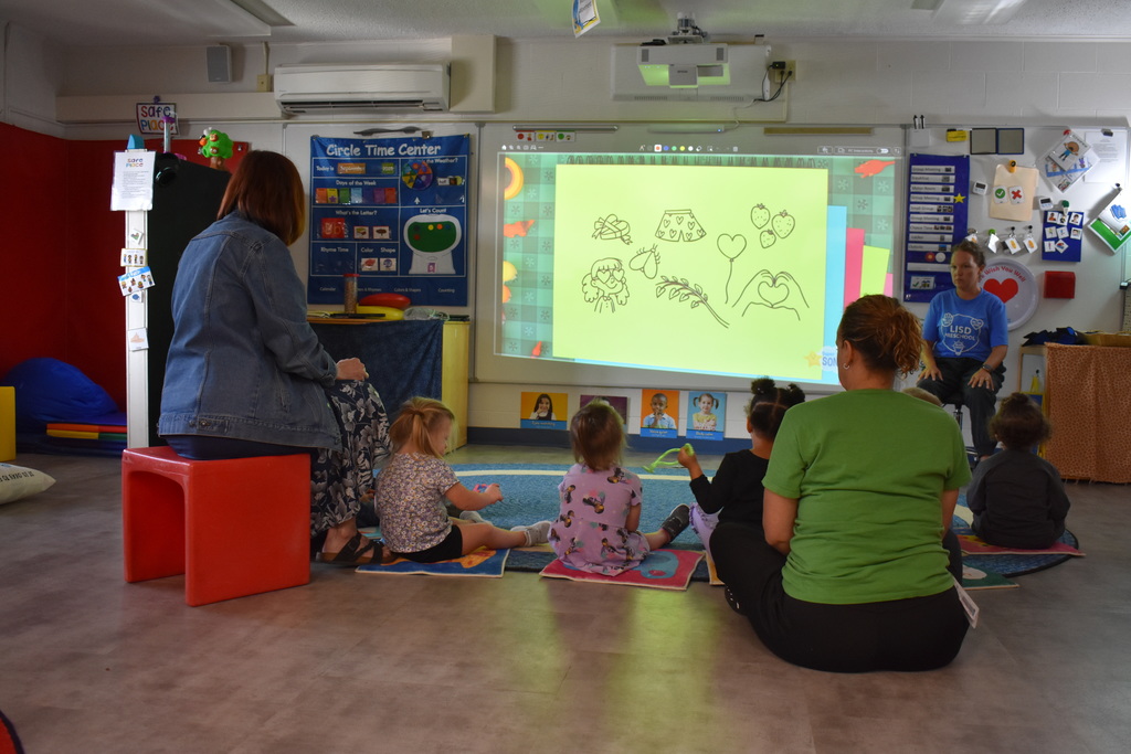 Students sitting in a half circle and following along with the teacher
