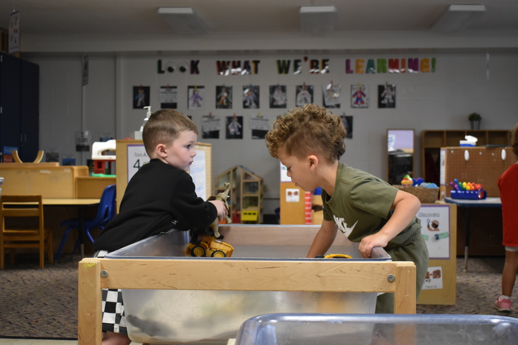 Two students playing trucks in a sensory tub