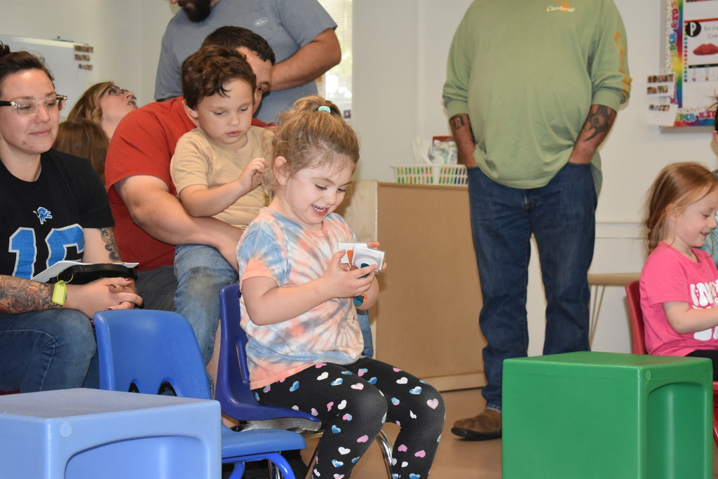 Child engaging with the activity given to her as she sits in a crowd