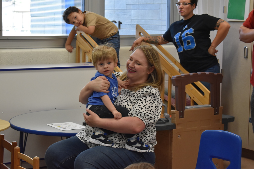 a parent and child seated at the event with another parent and child in the background