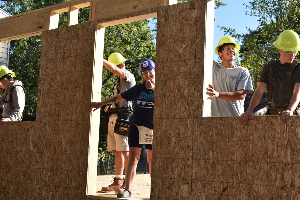 three students and the homeowner putting up the second wall 