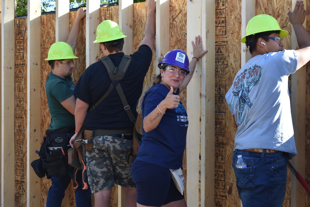 Students and homeowner holding up the first wall