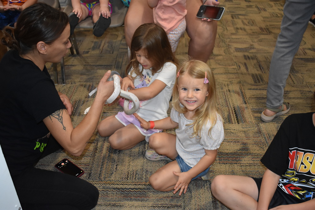 Two little girls engaging with a snake and one of the presenters