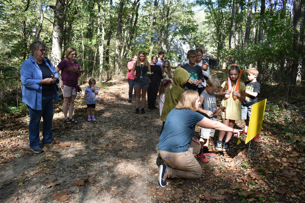 Kids on a StoryWalk as a staff members reads the story
