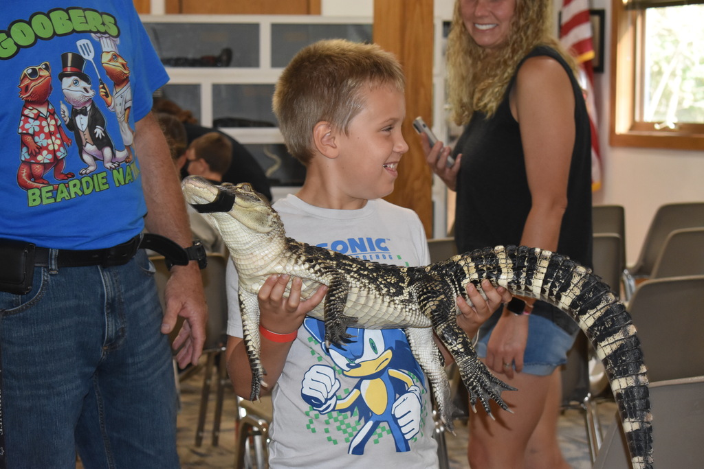a young boy holding an alligator