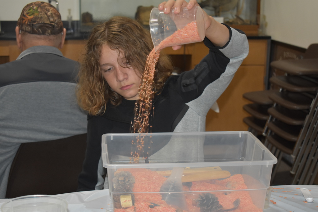A kid pouring orange rice into a container