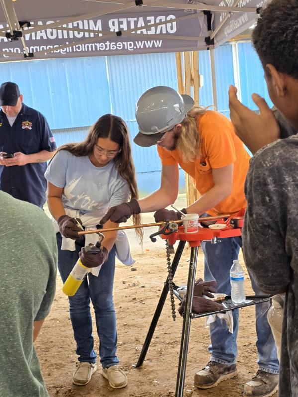 A student learning to weld in a hands on experience with an instructor from the trades