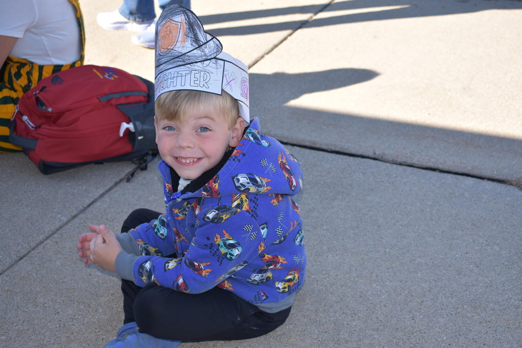 A student smiling at the camera with his firefighter cap on