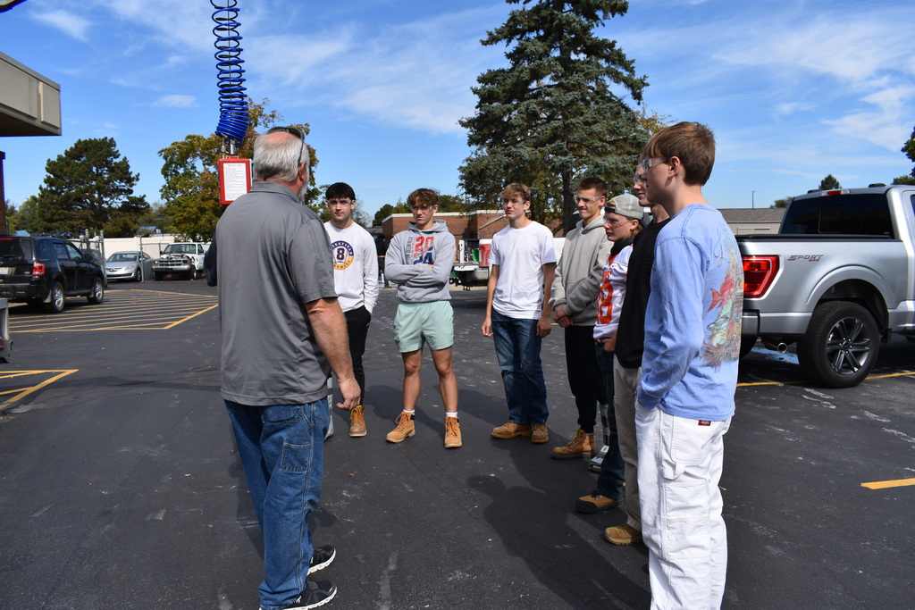 students listening to a guest speaker outside near the mule