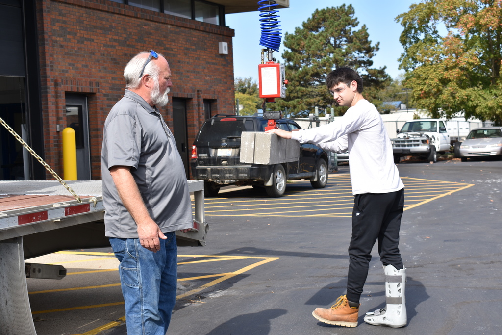 A student using the mule to move a block while the demonstrator looks on