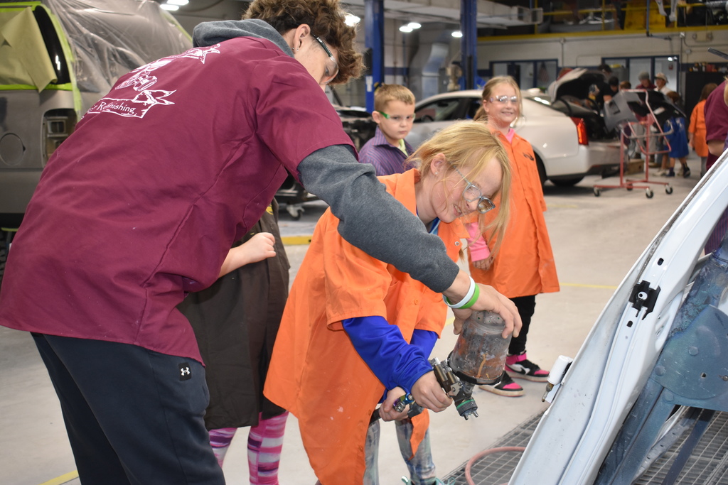 s student learns how to paint a car while a TECH center student assists