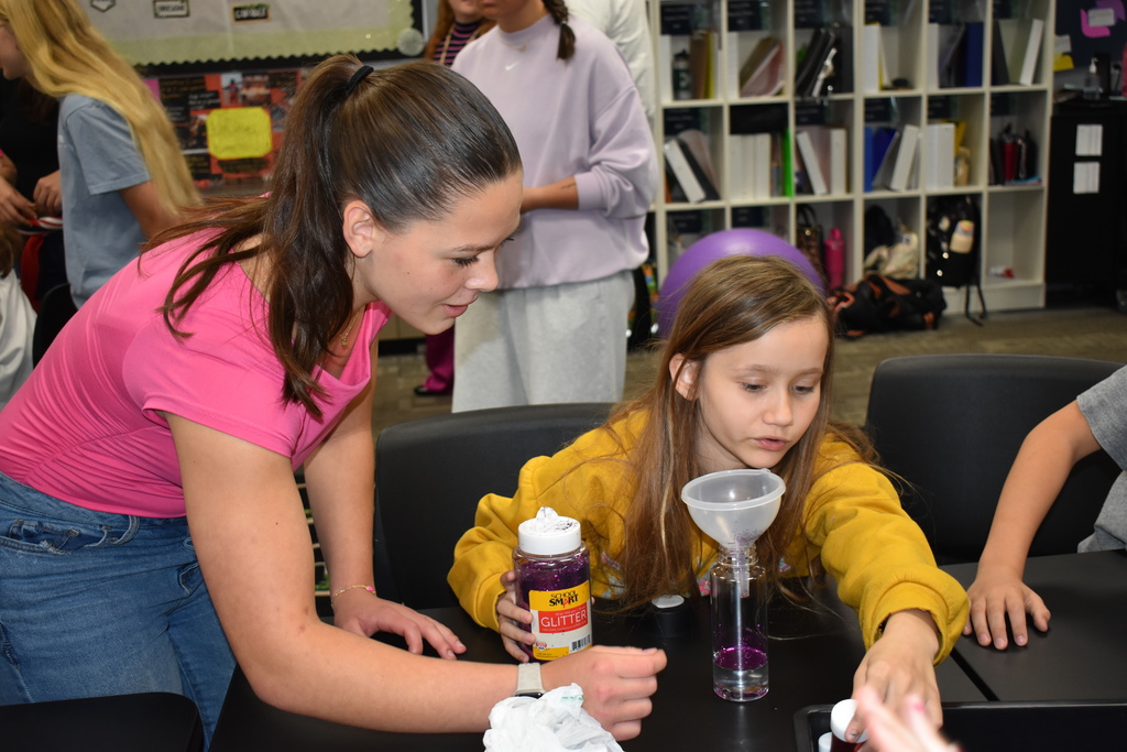 A high school student and elementary student work on a project together