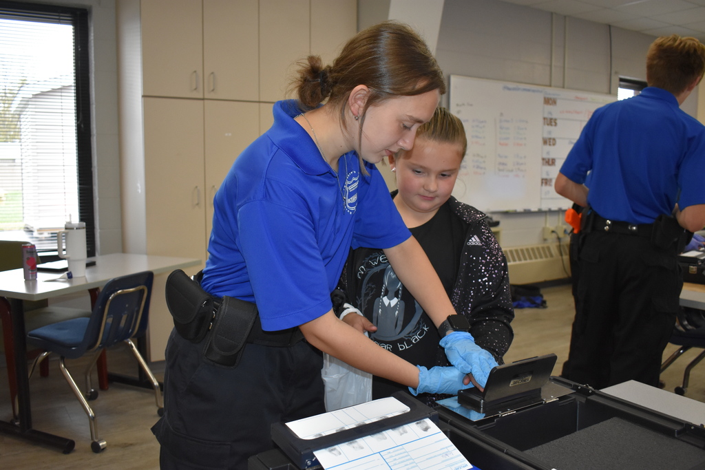 A student experiences fingerprinting with a Law Enforcement student