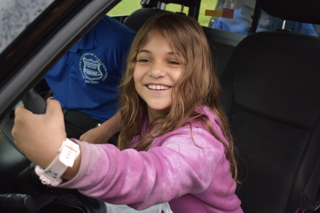 A student learns how to use a spotlight in a police car