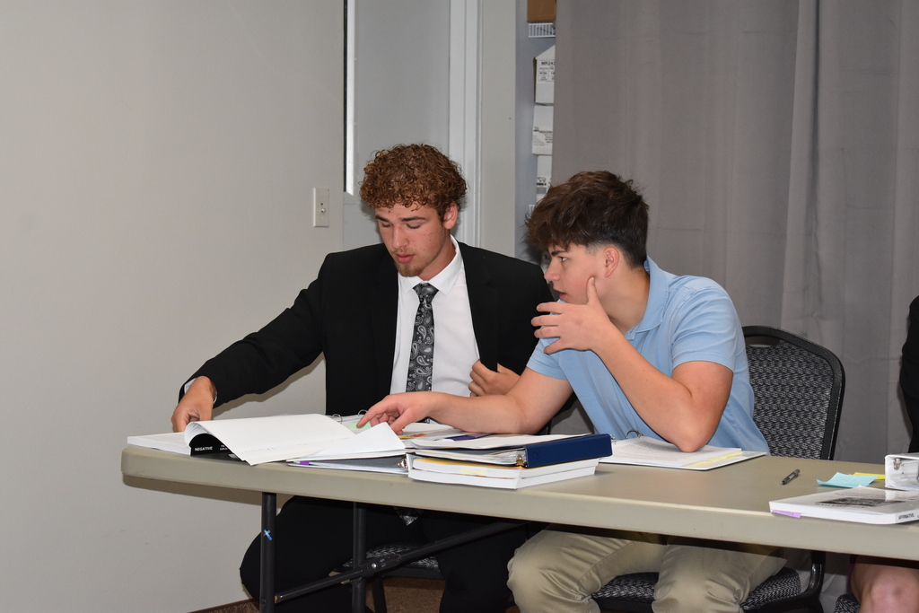 Two students whisper to each other about how to respond in their debate