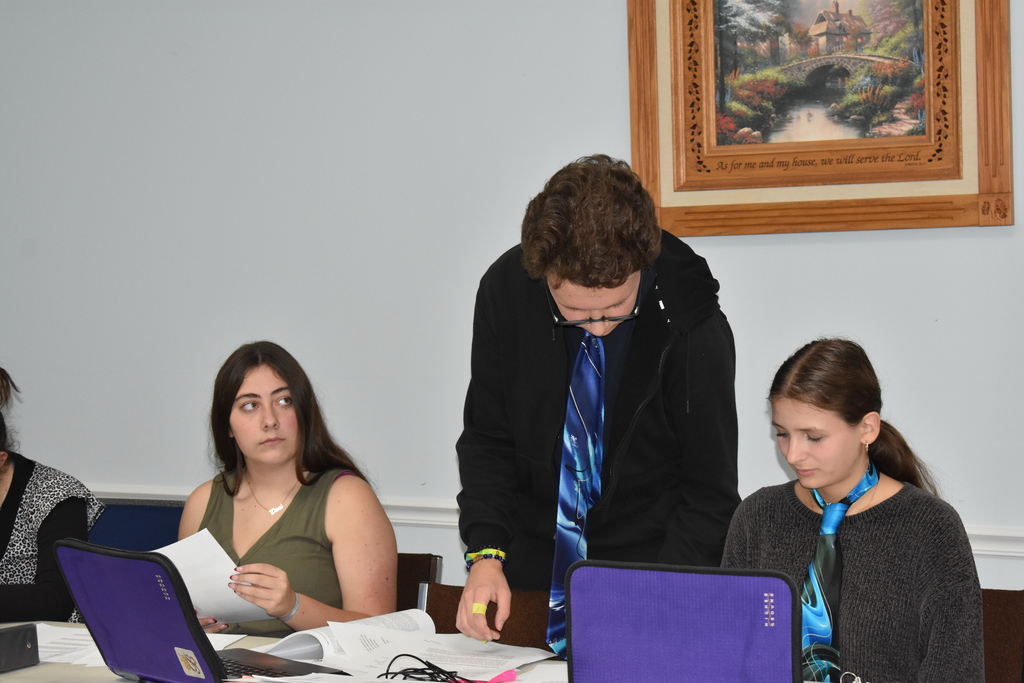 A student checks his evidence with his partner while opposition looks on 