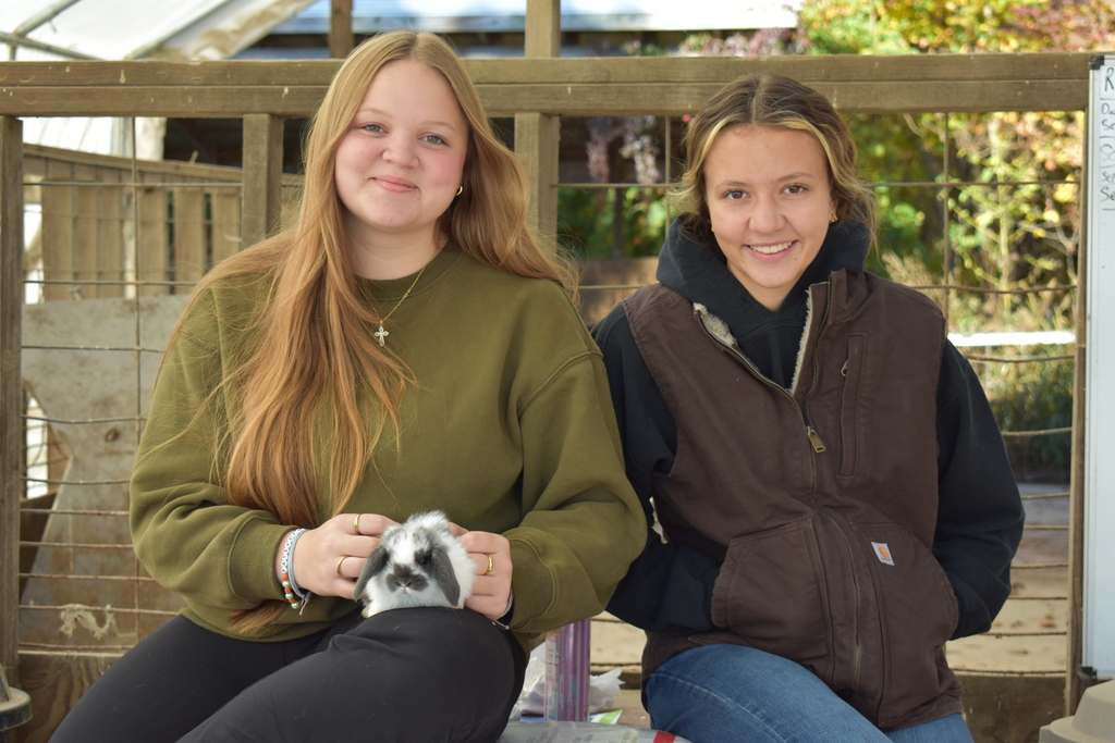 Two students posing with a rabbit
