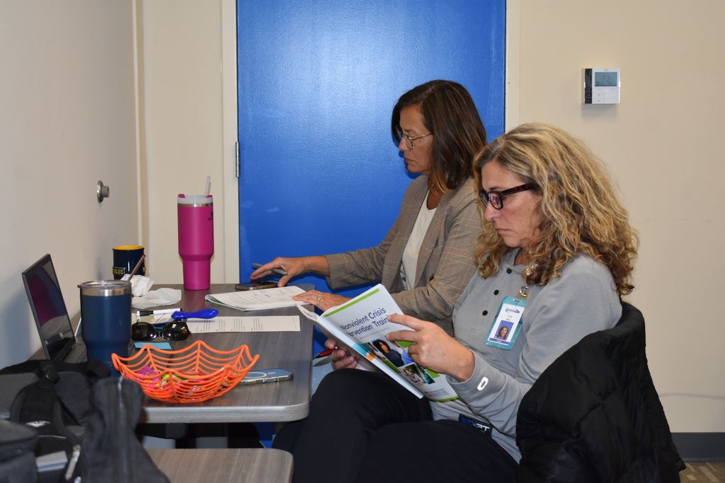 Two employees following along in a book