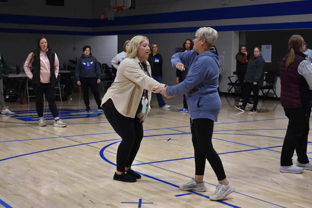 An instructor showing how to move out of the way of someone coming at them while others listening in