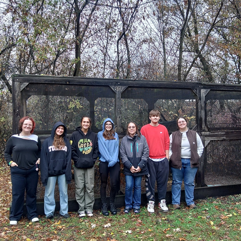 Students are standing in front of an outdoor enclosure for squirrels.