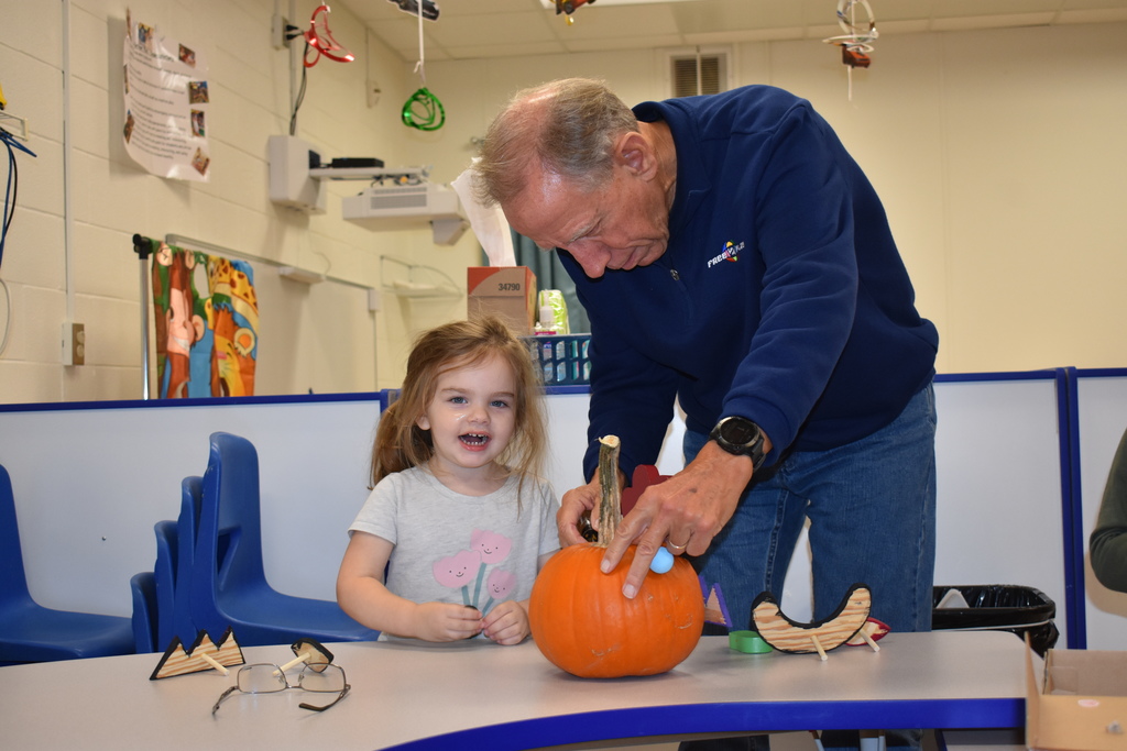 Volunteer helping a student with her pumpkin