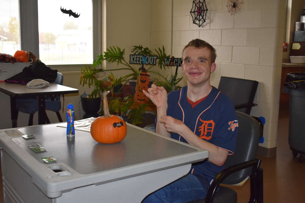 A student smiling at the camera with his pumpkin
