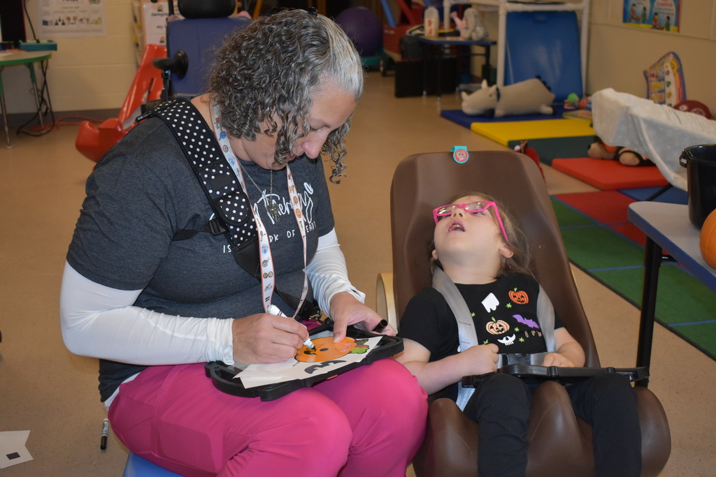 A teacher helping a student with her pumpkin