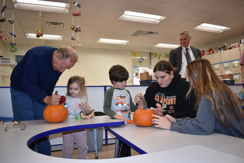 Volunteers helping students decorate their pumpkins