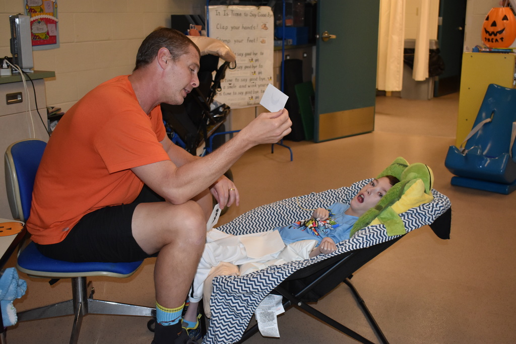 A teacher helping a student pick his mouth for the pumpkin