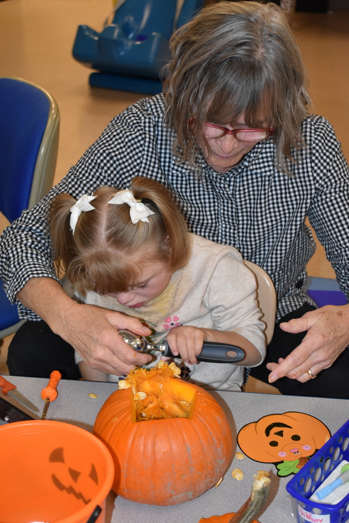 A teacher helping a student with her pumpkin