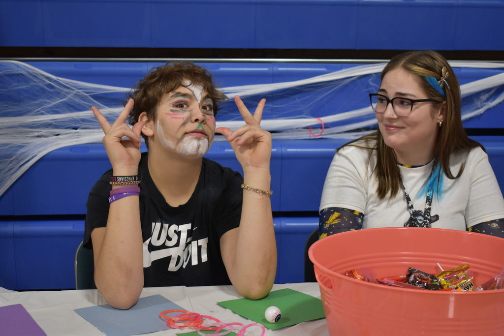 A student flashes the peace sign while his teacher smiles at him