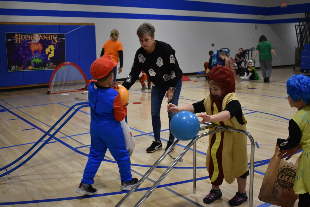 Students bowling while a teacher helps