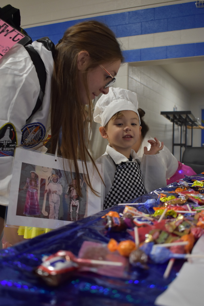 A student looks at candy to choose a piece while a teacher helps