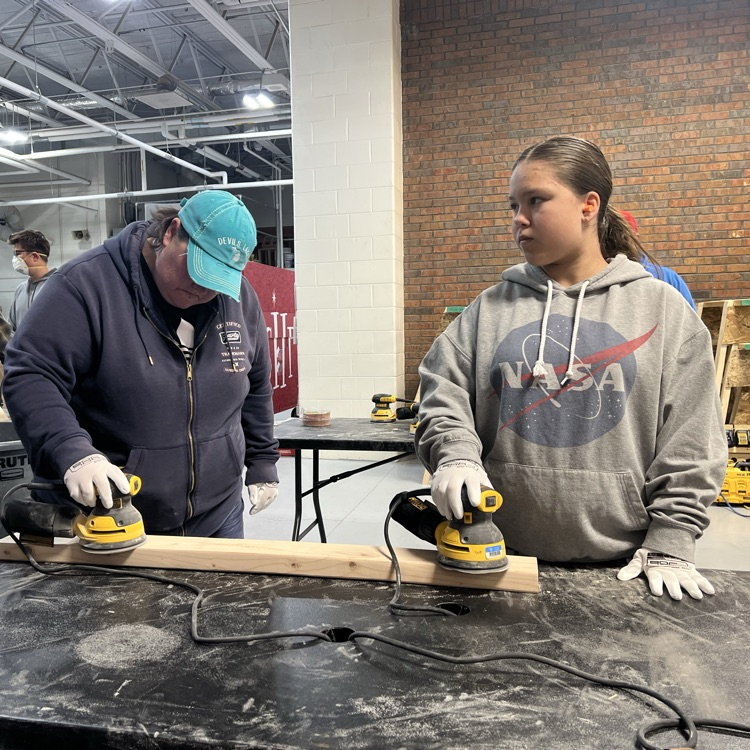 two people sanding wood