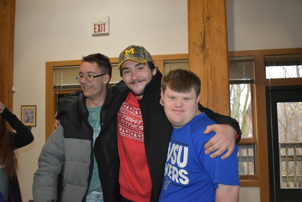 An Adrian College student posing with two students