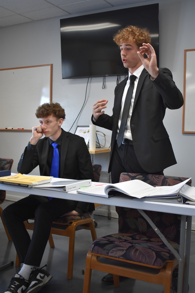 Student mid debate while another student listens on