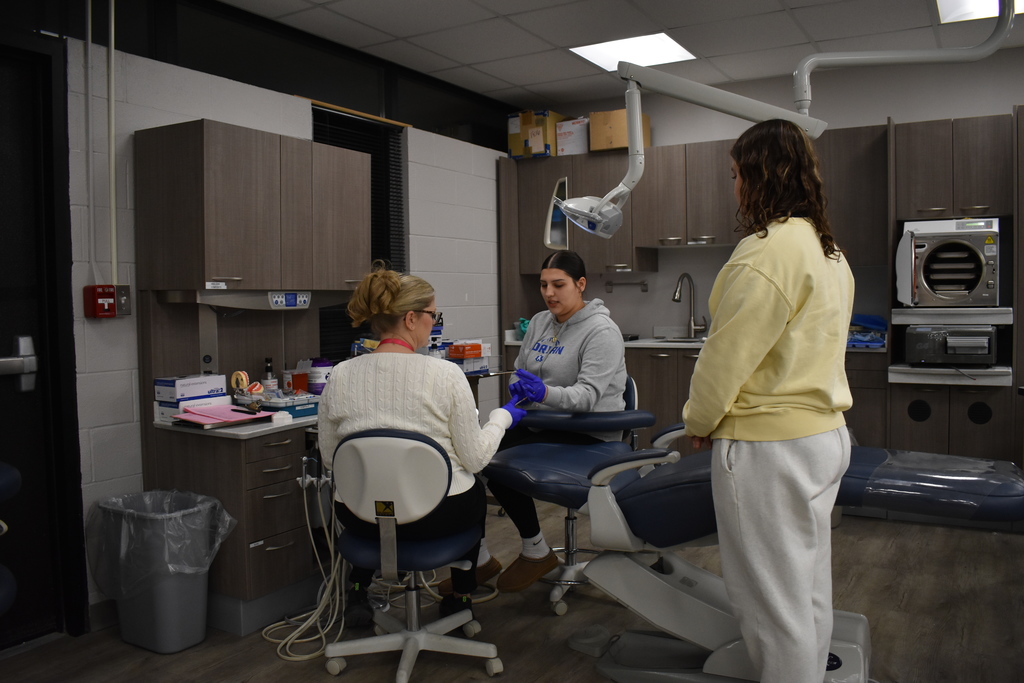 A dental student and instructor demonstrating for an interested family