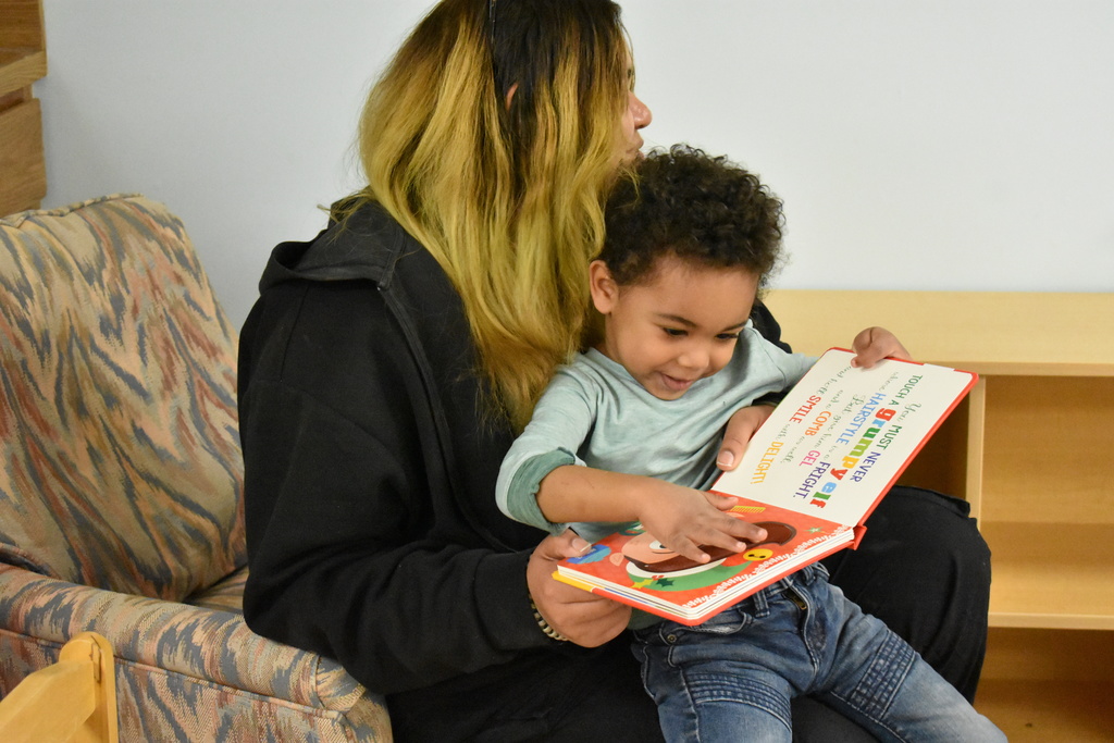 A child in his mom's lap while they read a book