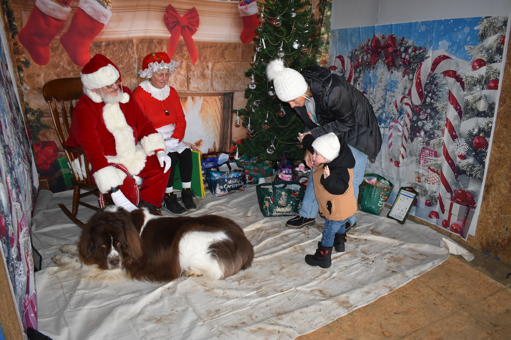 A little boy and his mom walking up to Santa and Mrs. Claus