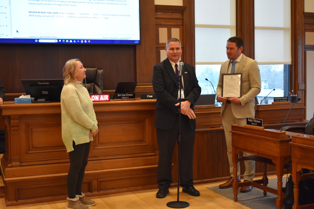 Mark Haag speaking at the meeting while two people look on near him