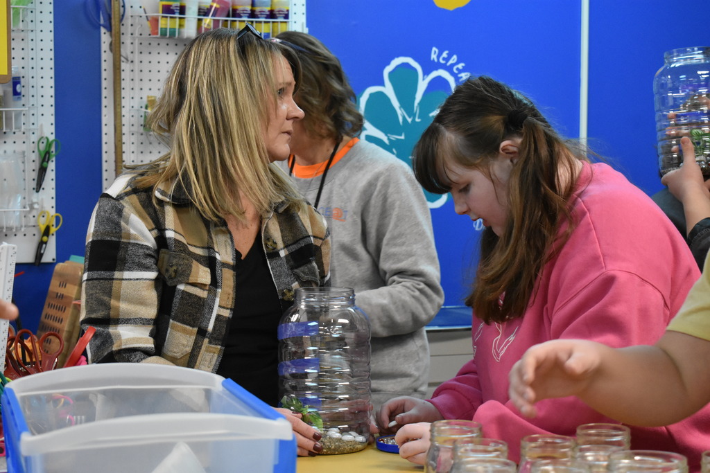 a student putting her aquarium together while a teacher looks on 